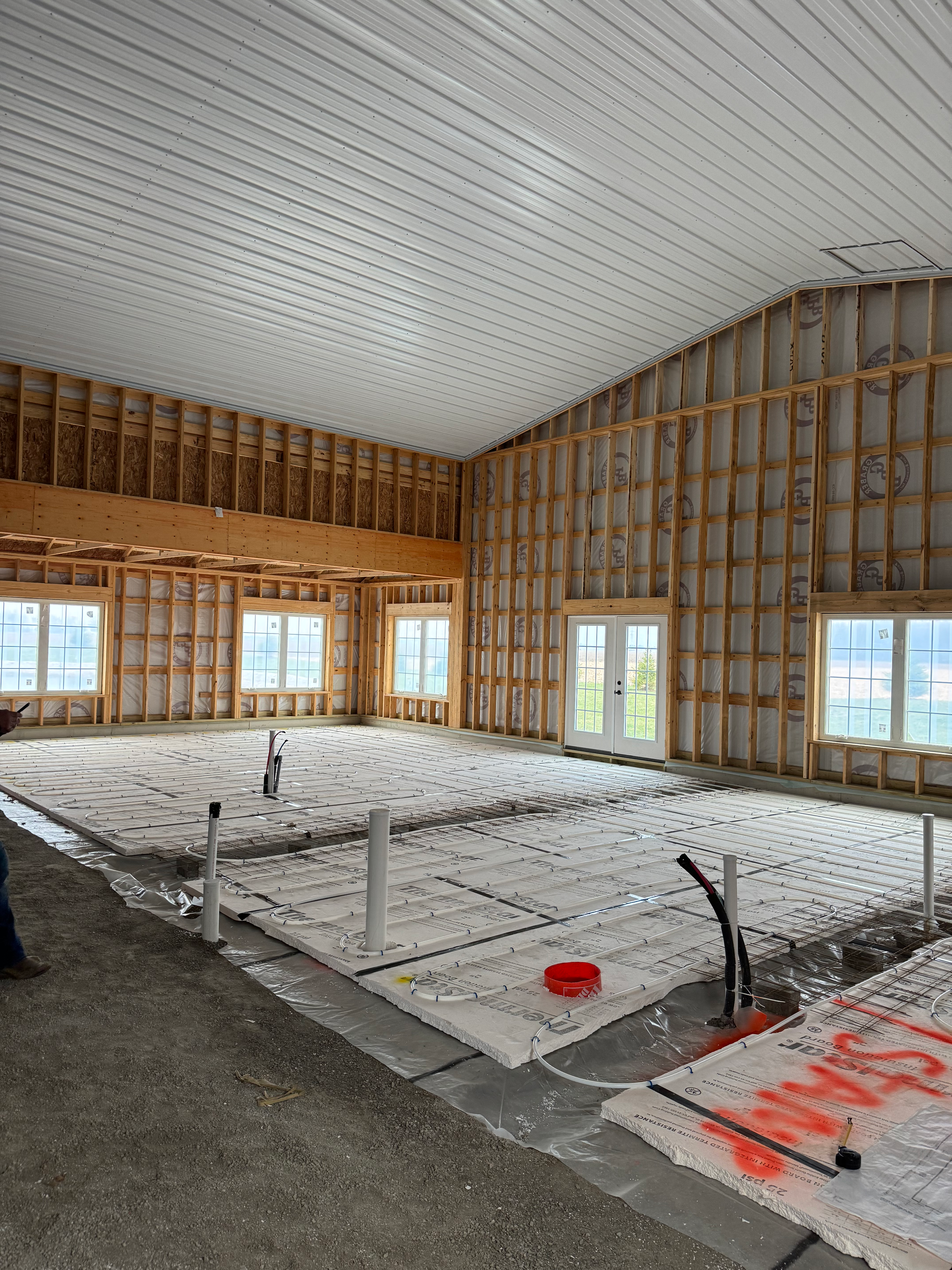 Radiant floor heating PEX tubing laid in a grid across a concrete slab in a large building under construction.