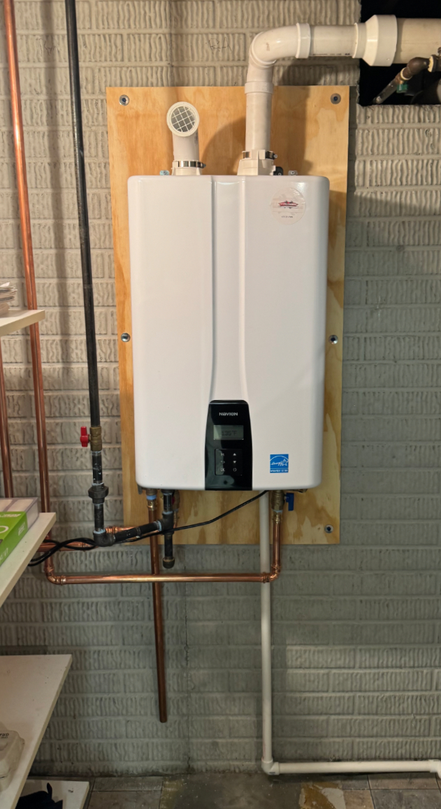 Wall-mounted Navien tankless water heater installed cleanly with copper line connections.